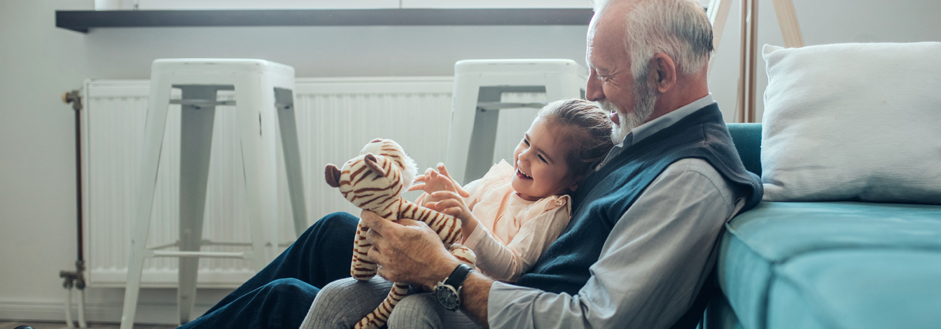 Little girl and her grandfather playing together at home.