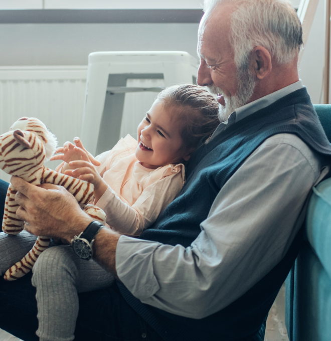 Little girl and her grandfather playing together at home.