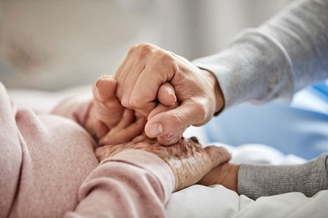 Image of a younger hand holding the hand of an older person