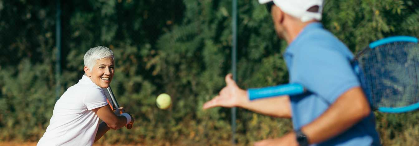 Couple playing tennis outside.