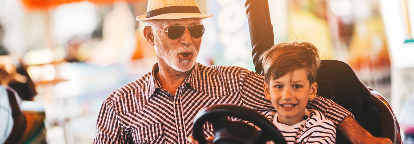 Grandfather and his son riding together in bumper cars.
