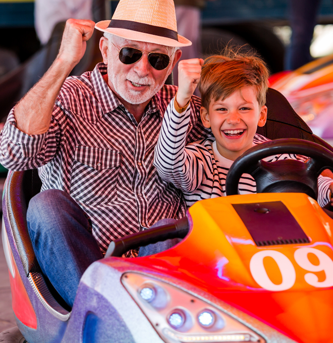 Grandfather and his son riding together in bumper cars.