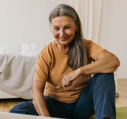 A smiling woman sits on the floor.